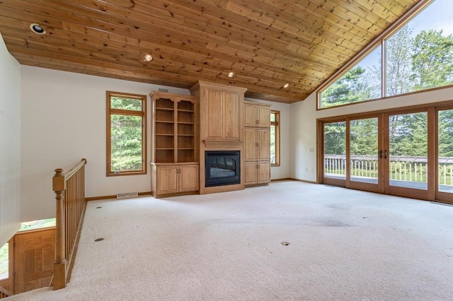 living area with light carpet, baseboards, visible vents, a glass covered fireplace, and wooden ceiling