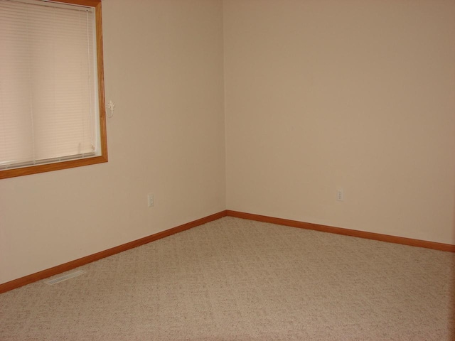 carpeted empty room featuring visible vents and baseboards