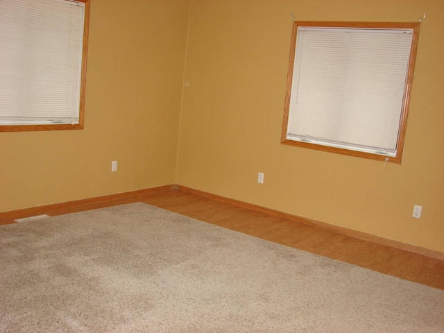 unfurnished room with wood finished floors, visible vents, and baseboards