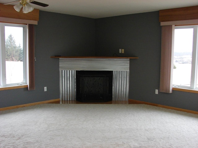 unfurnished living room featuring carpet floors, a fireplace, baseboards, and ceiling fan