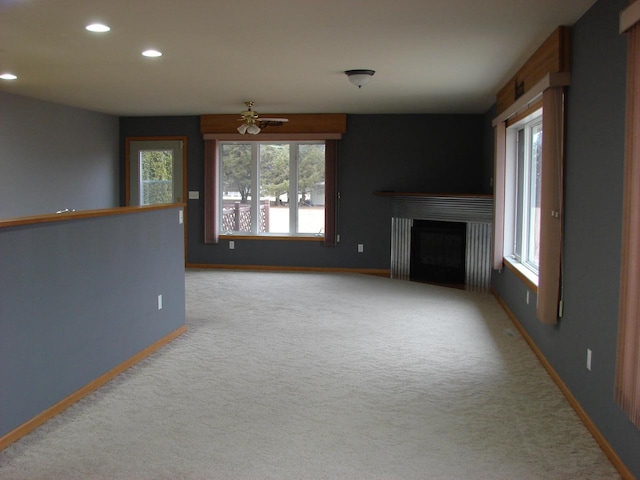 unfurnished living room with plenty of natural light, a fireplace, carpet flooring, and baseboards