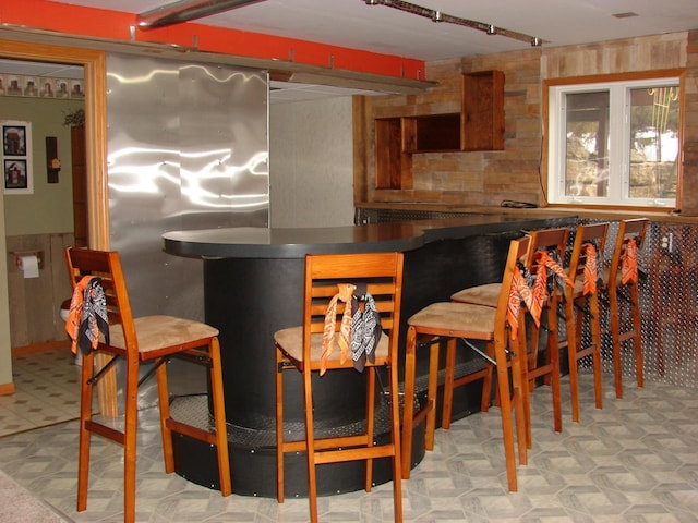 bar with a dry bar, a wainscoted wall, and tile patterned floors