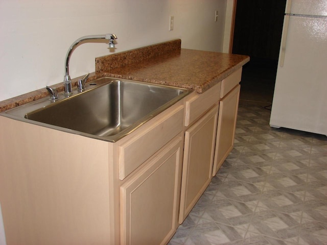 kitchen featuring light floors, a sink, and freestanding refrigerator