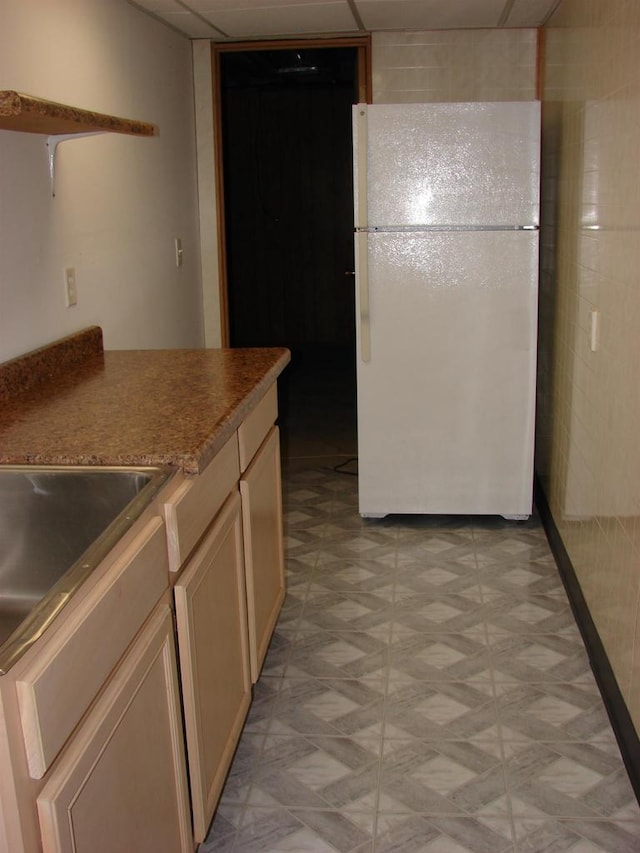 kitchen with light floors, a sink, and freestanding refrigerator