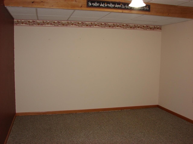 spare room with carpet, a drop ceiling, and baseboards