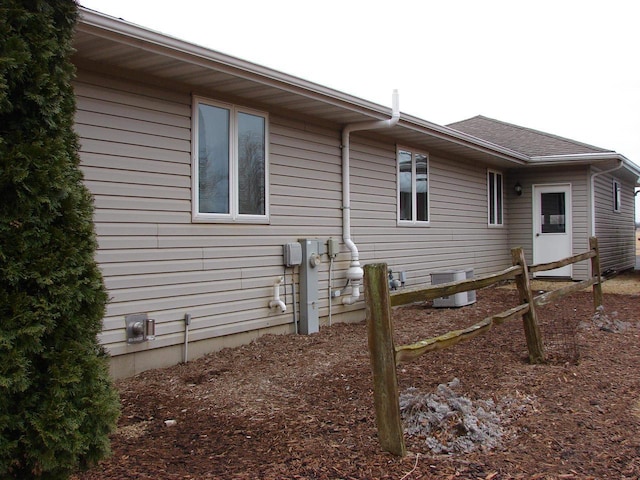 view of side of home featuring a shingled roof and cooling unit