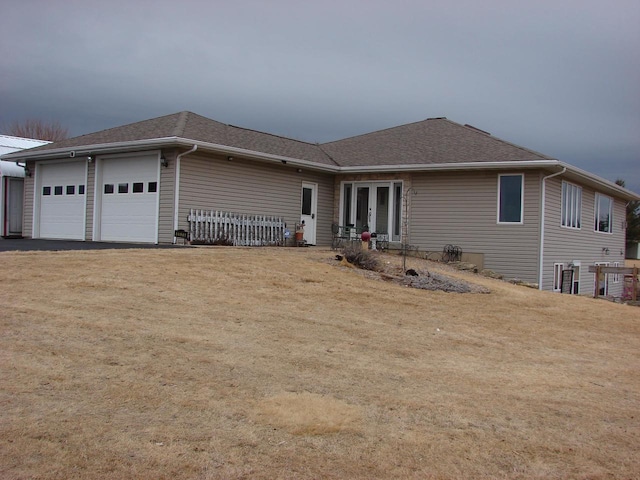 single story home featuring driveway, roof with shingles, an attached garage, french doors, and a front yard