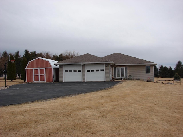 ranch-style house featuring a storage unit, an attached garage, a front yard, an outdoor structure, and driveway