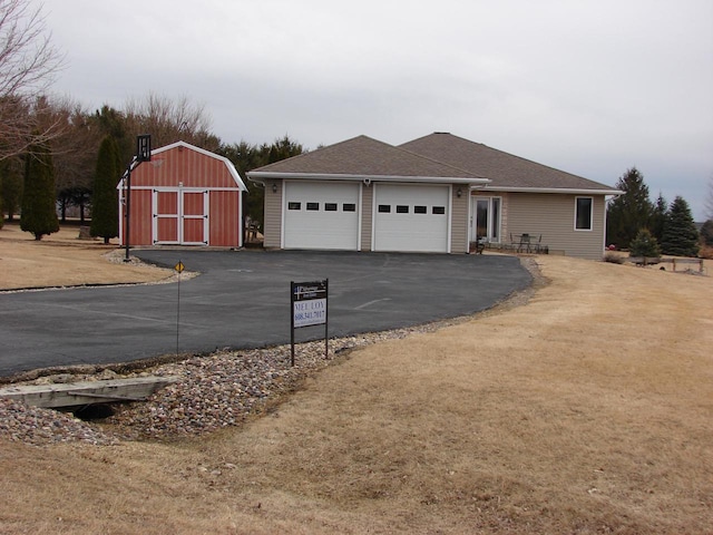 view of front of house featuring aphalt driveway, an outdoor structure, and an attached garage