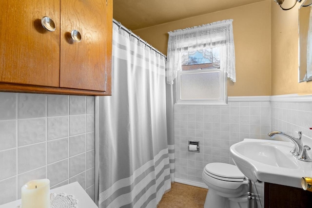 bathroom with tile walls, toilet, wainscoting, vanity, and tile patterned flooring