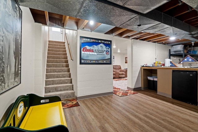 interior space featuring concrete block wall, fridge, stairway, and wood finished floors