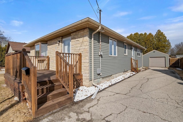 view of front of property featuring a garage, driveway, an outdoor structure, and a wooden deck