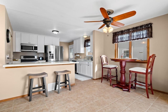 kitchen featuring appliances with stainless steel finishes, white cabinetry, a peninsula, and a breakfast bar area