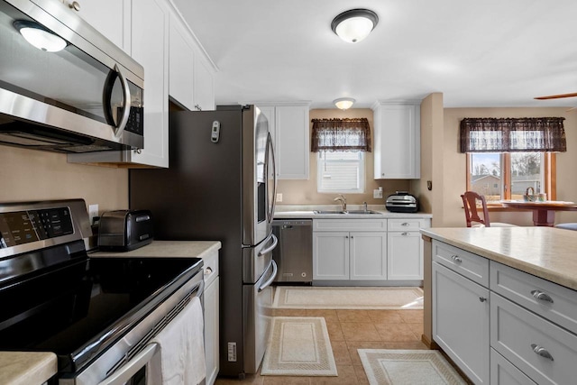 kitchen featuring stainless steel appliances, a sink, light countertops, and a healthy amount of sunlight