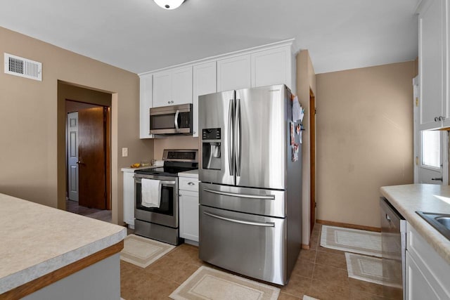 kitchen with light tile patterned floors, visible vents, appliances with stainless steel finishes, light countertops, and white cabinetry