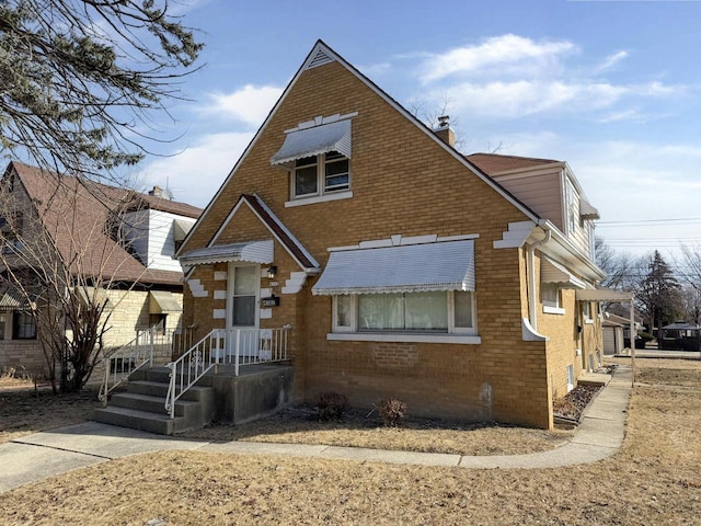 bungalow-style house with a chimney and brick siding