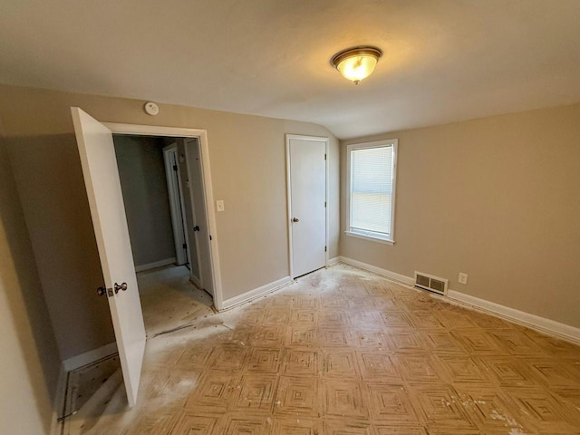 empty room with baseboards, visible vents, and vaulted ceiling