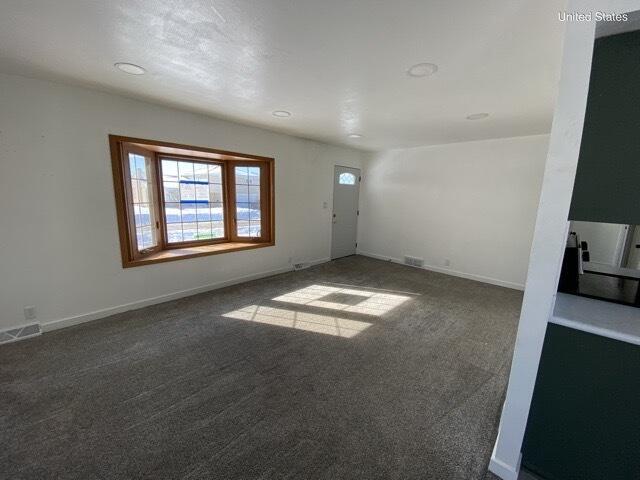 empty room featuring carpet floors, visible vents, and baseboards