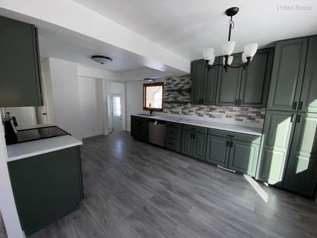 kitchen featuring wood finished floors, a sink, light countertops, backsplash, and dishwasher