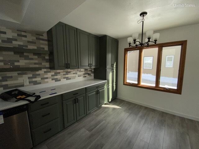 kitchen featuring baseboards, backsplash, dishwasher, and wood finished floors