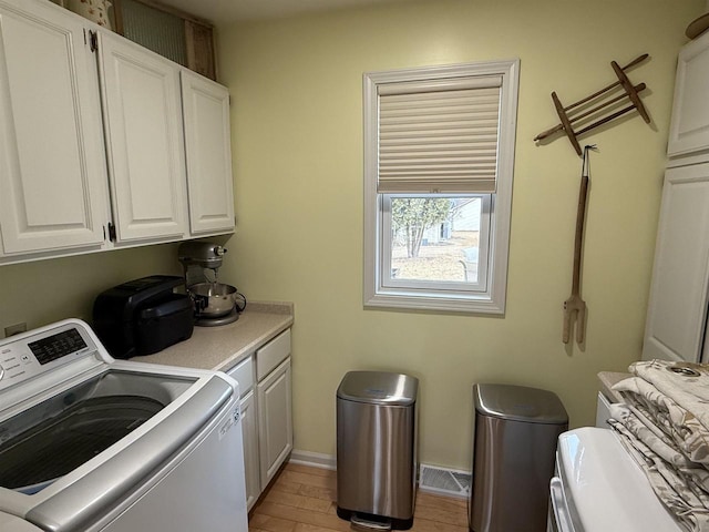 laundry room with baseboards, visible vents, washer / clothes dryer, cabinet space, and light wood-type flooring