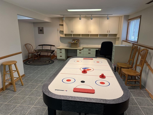 rec room featuring dark tile patterned floors, baseboards, built in study area, and electric panel