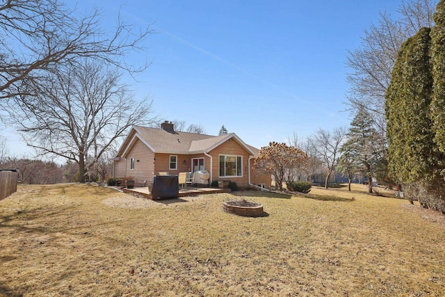 rear view of house with a chimney, a yard, a fire pit, and a patio