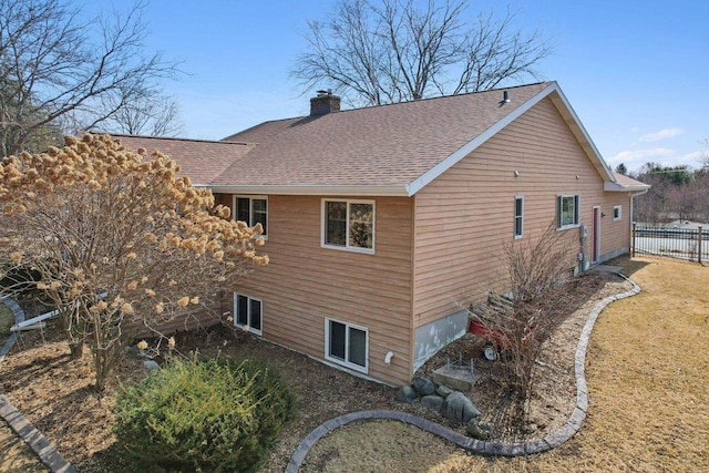 view of side of property with a shingled roof, fence, and a chimney