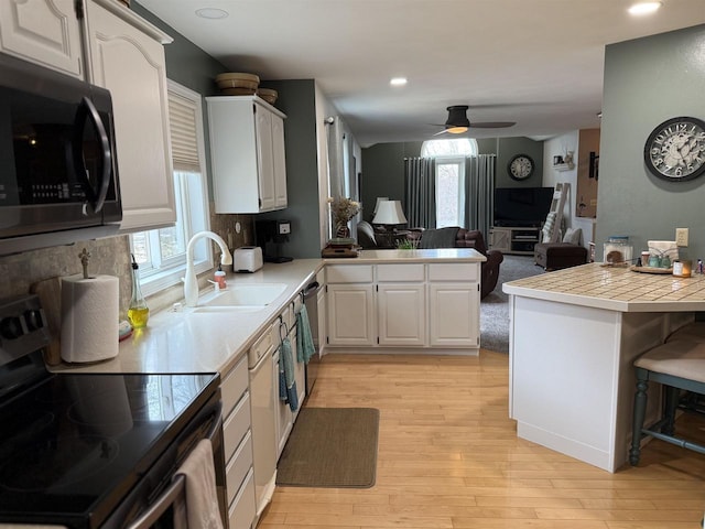 kitchen with stainless steel electric stove, plenty of natural light, a peninsula, and a sink