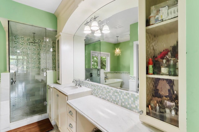 bathroom featuring a stall shower, a freestanding tub, vanity, and an inviting chandelier