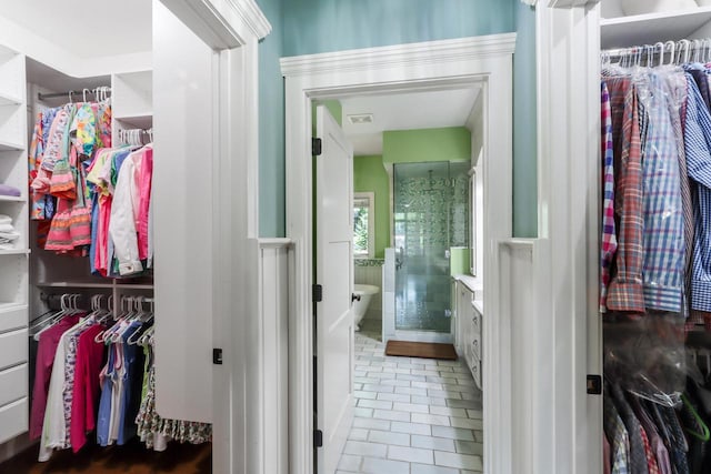 bathroom featuring vanity, a walk in closet, visible vents, and tile patterned floors