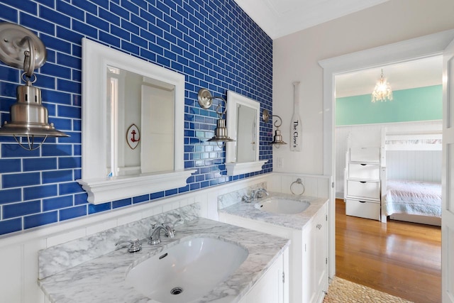 ensuite bathroom with connected bathroom, wood finished floors, vanity, and decorative backsplash