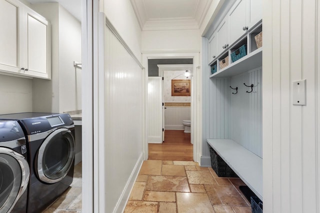 washroom with cabinet space, crown molding, washer and clothes dryer, and stone tile flooring