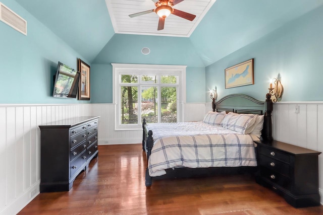 bedroom with a wainscoted wall, visible vents, a ceiling fan, vaulted ceiling, and wood finished floors