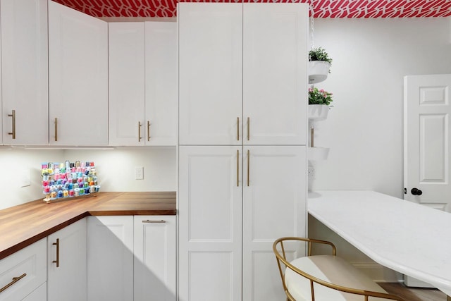 kitchen with brick ceiling, open shelves, wood counters, and white cabinetry