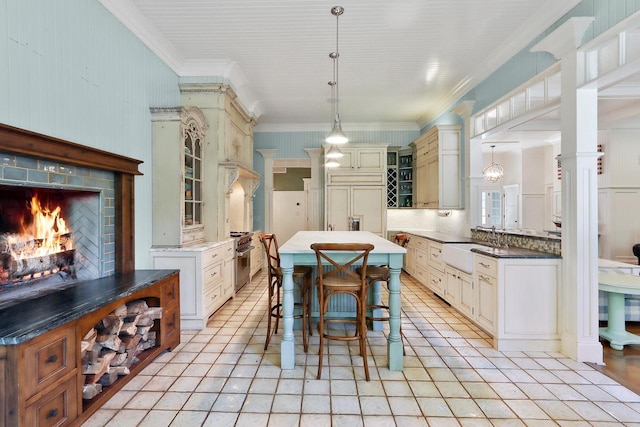 dining area with light tile patterned floors, a lit fireplace, decorative columns, and crown molding