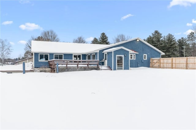 view of front of house featuring stucco siding, fence, and a wooden deck