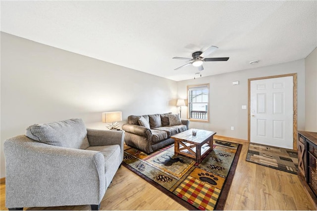 living room featuring ceiling fan, a textured ceiling, and light wood-style flooring