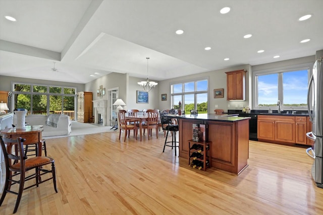 kitchen with brown cabinets, light wood finished floors, dark countertops, dishwasher, and a kitchen breakfast bar