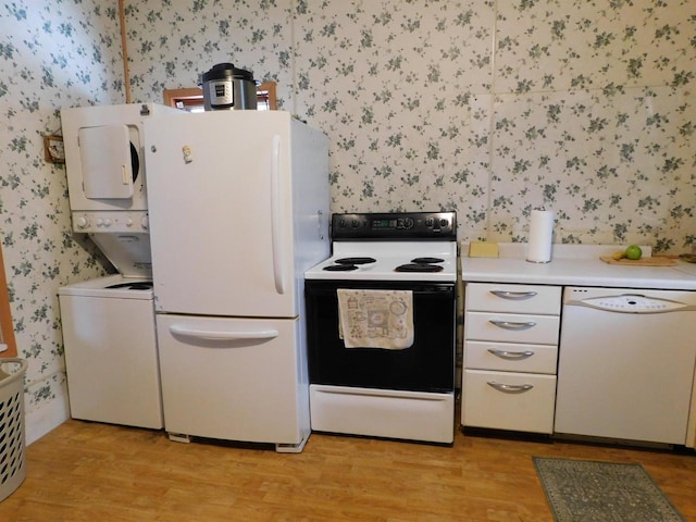 kitchen featuring stacked washer / drying machine, white appliances, light wood-type flooring, and wallpapered walls