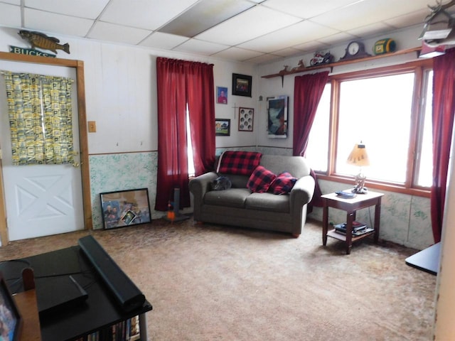 carpeted living area with a paneled ceiling