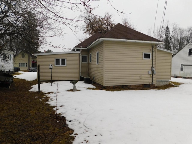 snow covered back of property featuring central AC unit