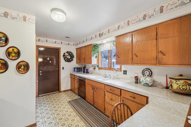 kitchen featuring black dishwasher, light countertops, stainless steel microwave, a sink, and baseboards