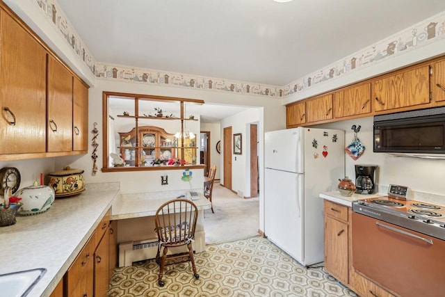 kitchen featuring built in desk, light countertops, electric range, freestanding refrigerator, and black microwave