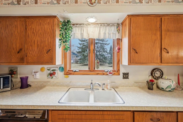 kitchen with dishwashing machine, a sink, light countertops, brown cabinetry, and stainless steel microwave