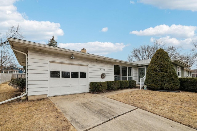 single story home featuring a garage, concrete driveway, a chimney, and fence