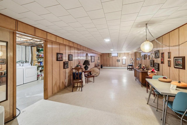 interior space featuring light floors, a baseboard radiator, washer and clothes dryer, and wood walls