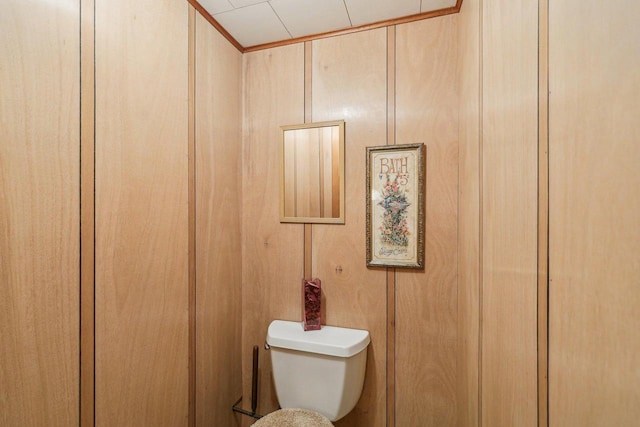 bathroom featuring toilet and wooden walls