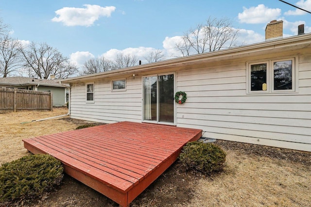 exterior space with a deck, fence, and a chimney