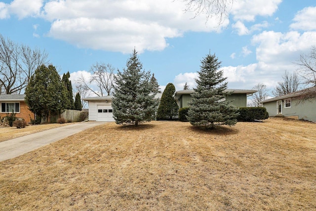 view of front of house with an attached garage, fence, concrete driveway, and a front yard